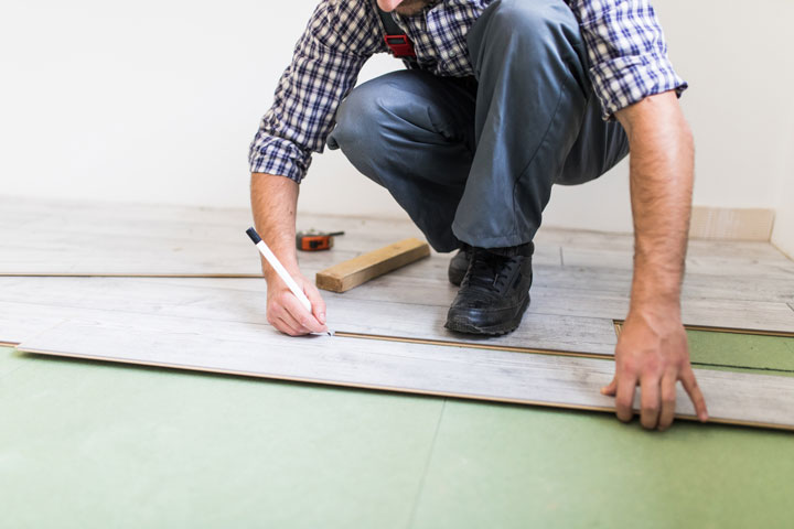 young worker lining floor with laminated flooring boards
